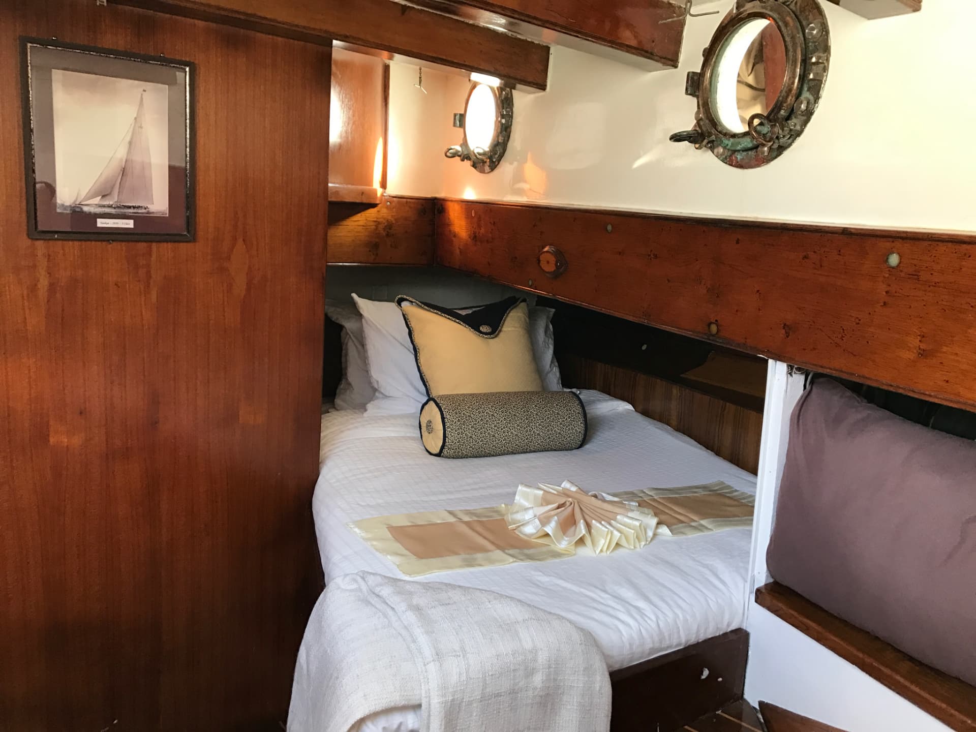 Mahogany guest cabin with brass portholes aboard Seraph